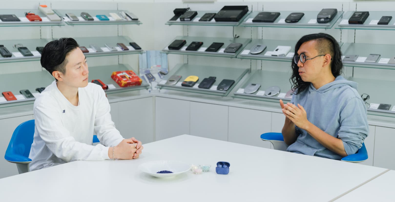 本坊健一郎さんと加藤功将さんが、再生プラスチックを用いた素材を手元に、向かい合って座り、真面目に話し合っている写真。