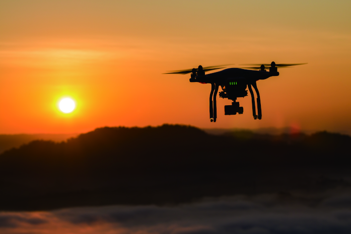 夕焼けの山岳で飛行中のドローン