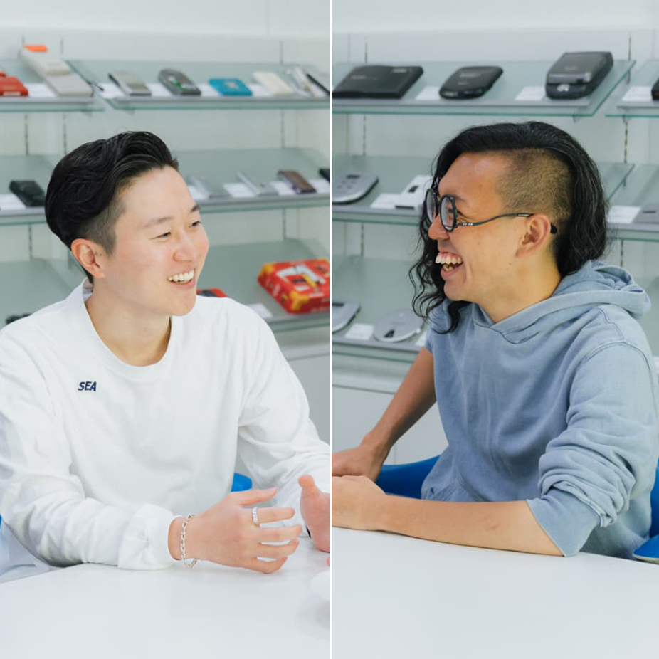 本坊健一郎さんと加藤功将さんが、再生プラスチックを用いた素材を手元に、向かい合って座り、笑っている写真。