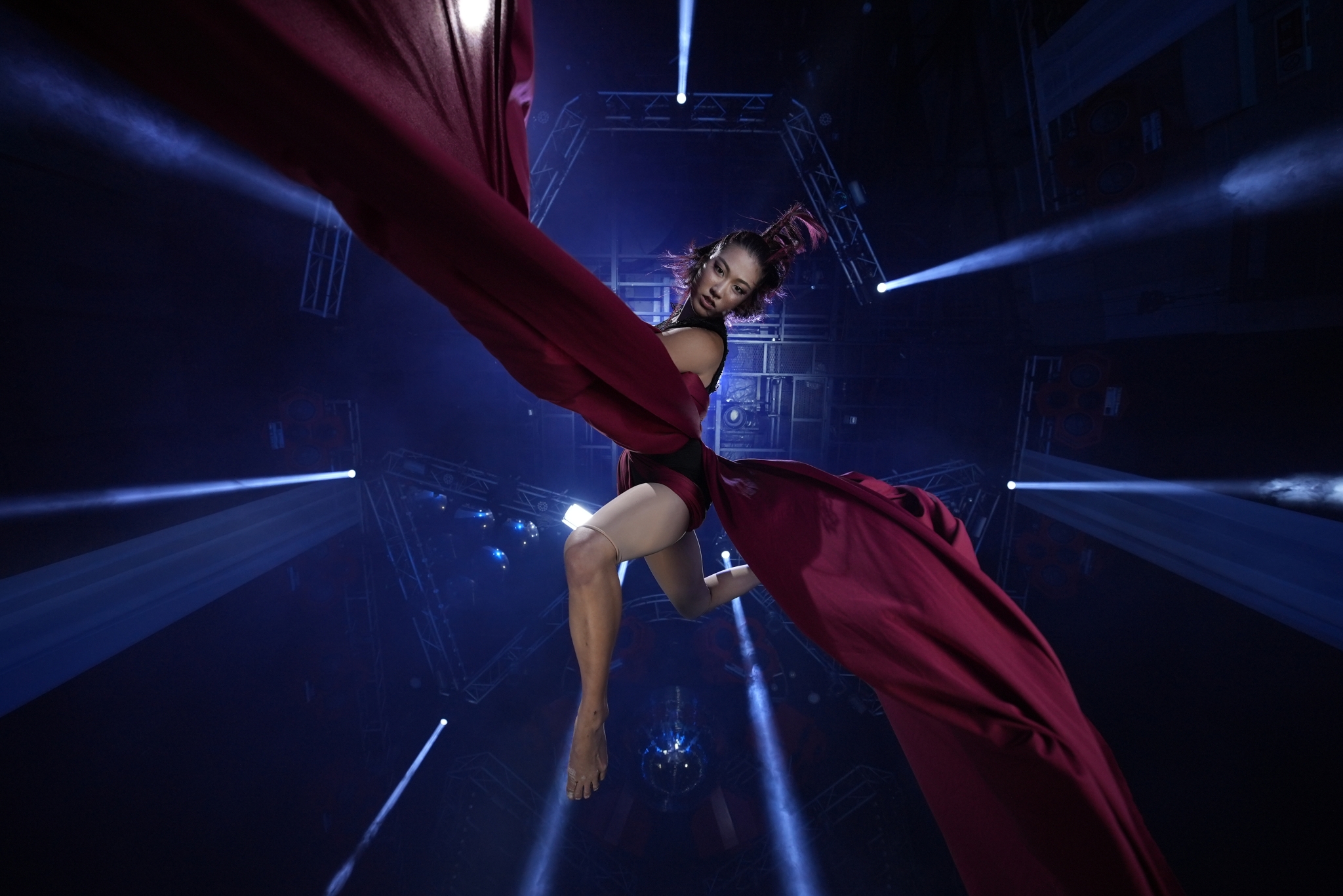 Female dancer with dress billowing out either side against a lowlight deep blue backdrop Click to open modal