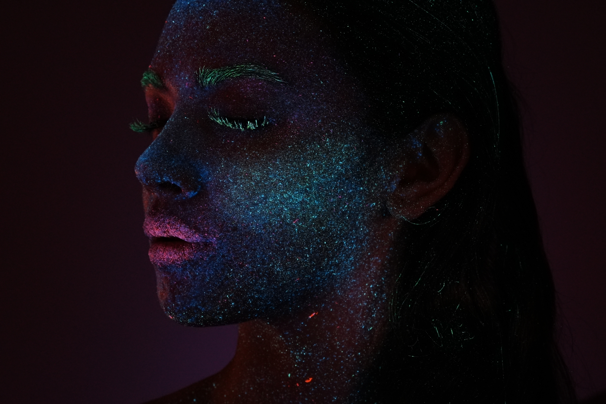 Close-up of a female face in the dark illuminated by luminescent make-up Click to open modal