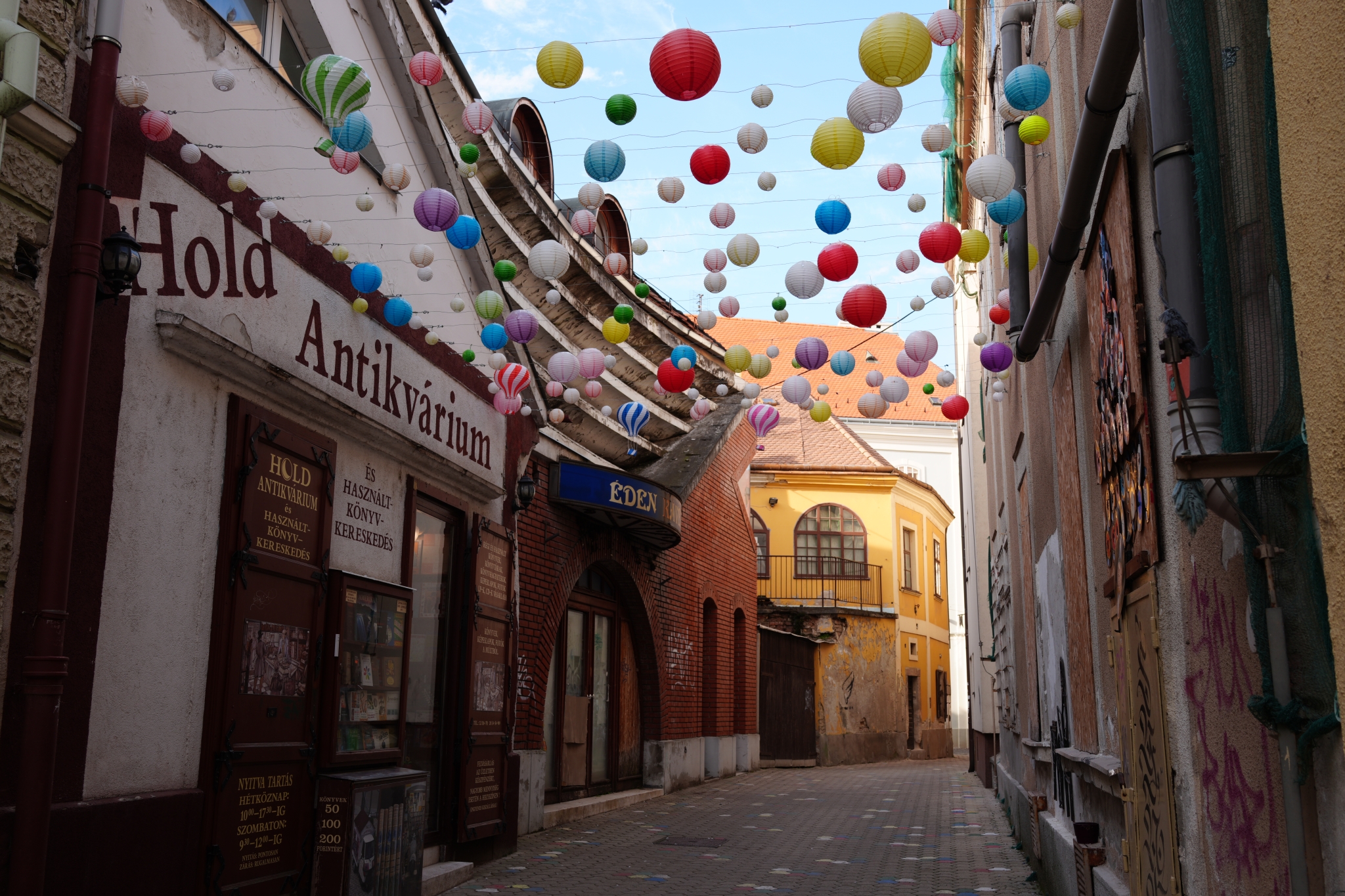 A sample image of showing a street corner where many colorful balloons are flying up all over the road, taken in Creative Look VV mode. Click to open modal