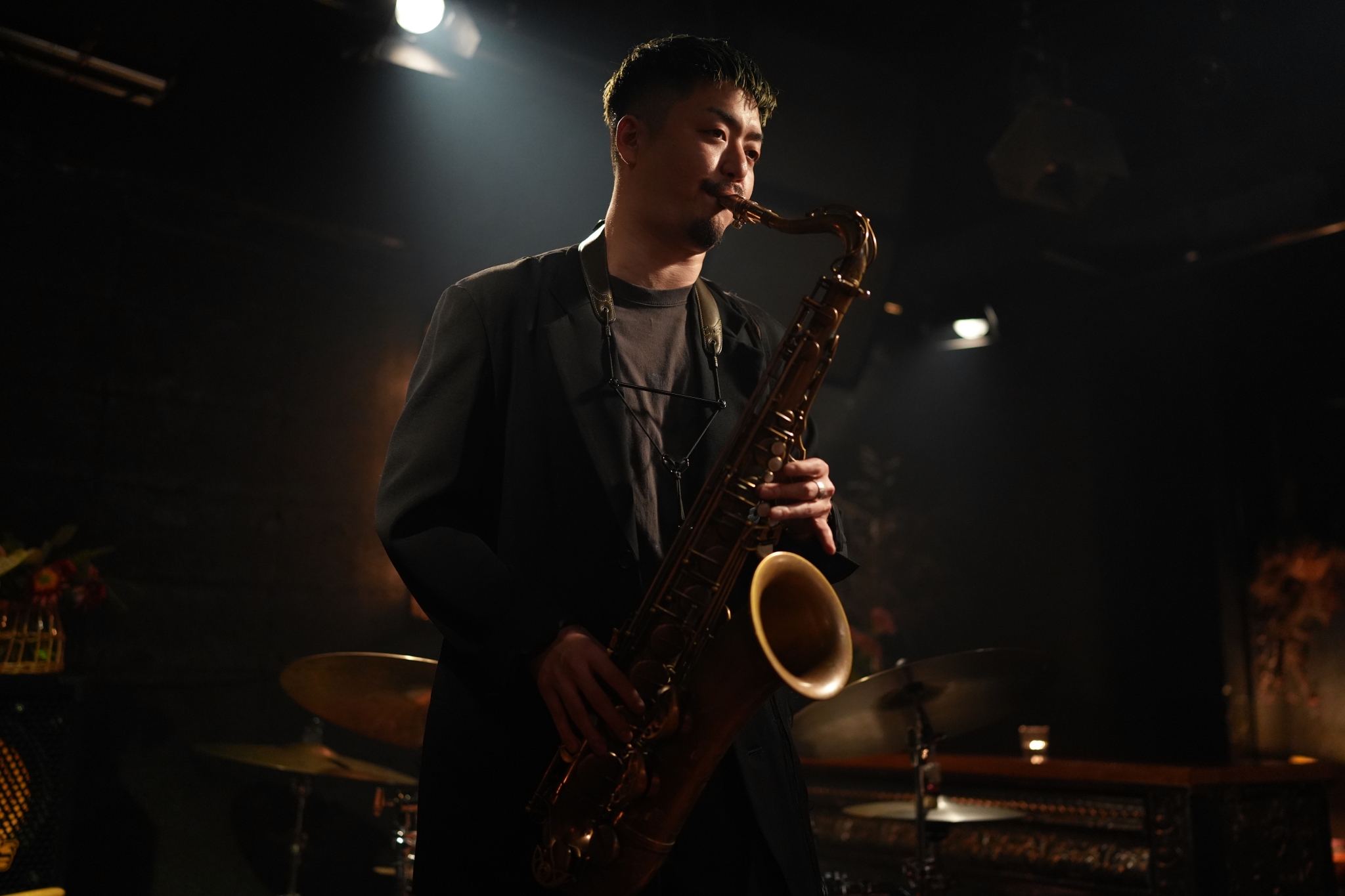 A man playing the saxophone in a dark room Click to open modal