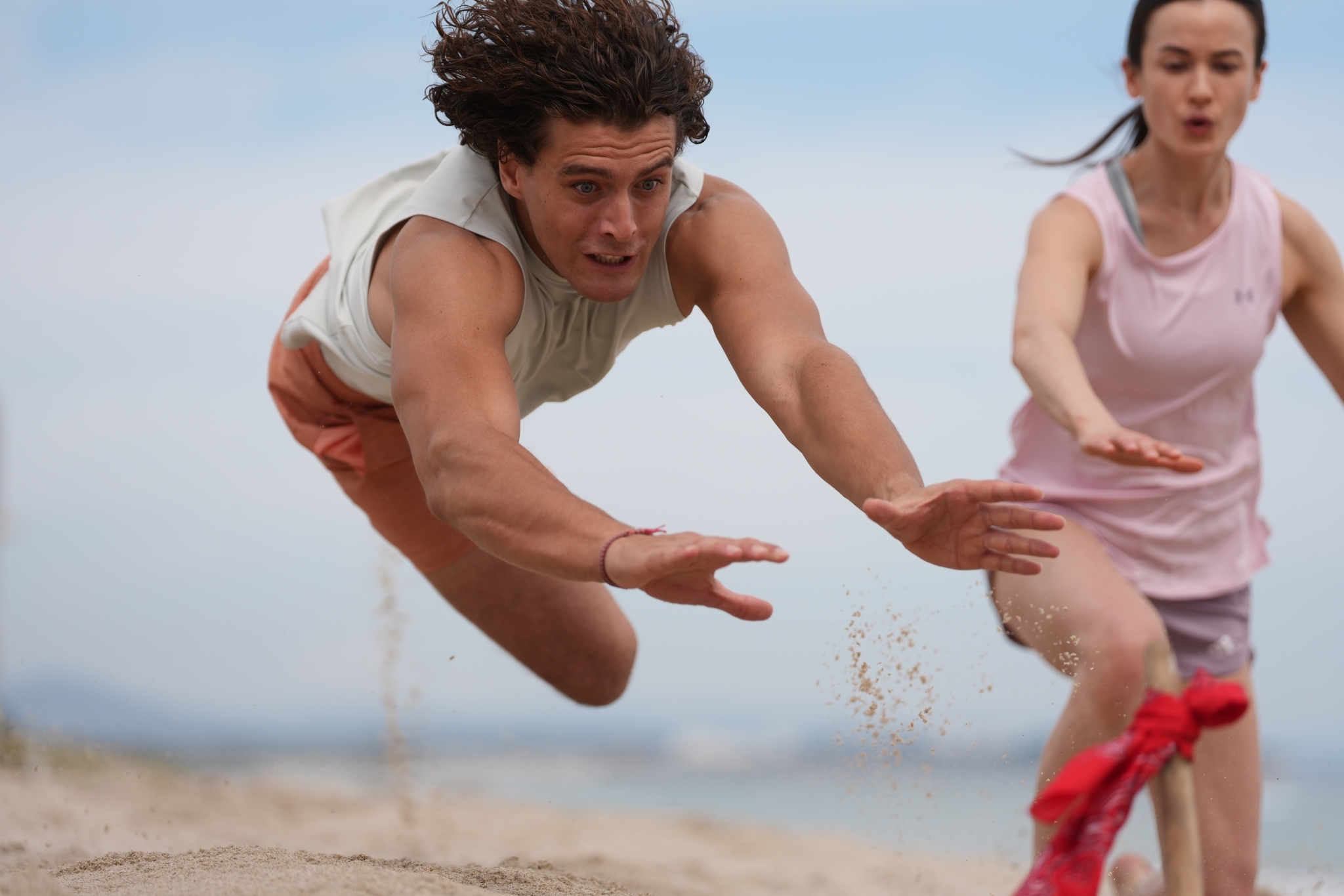 A man jumping to catch a beach flag Click to open modal