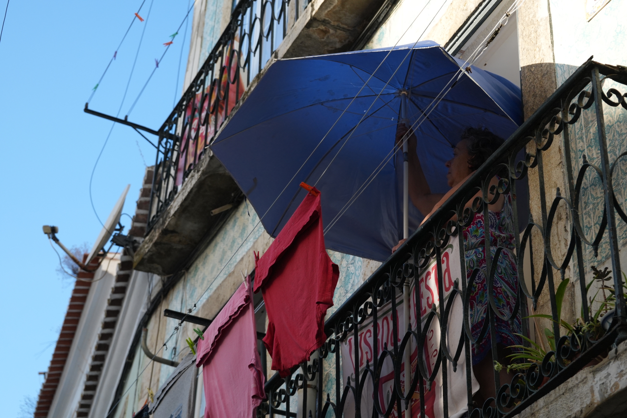 A woman hanging an umbrella out to dry on a balcony Click to open modal