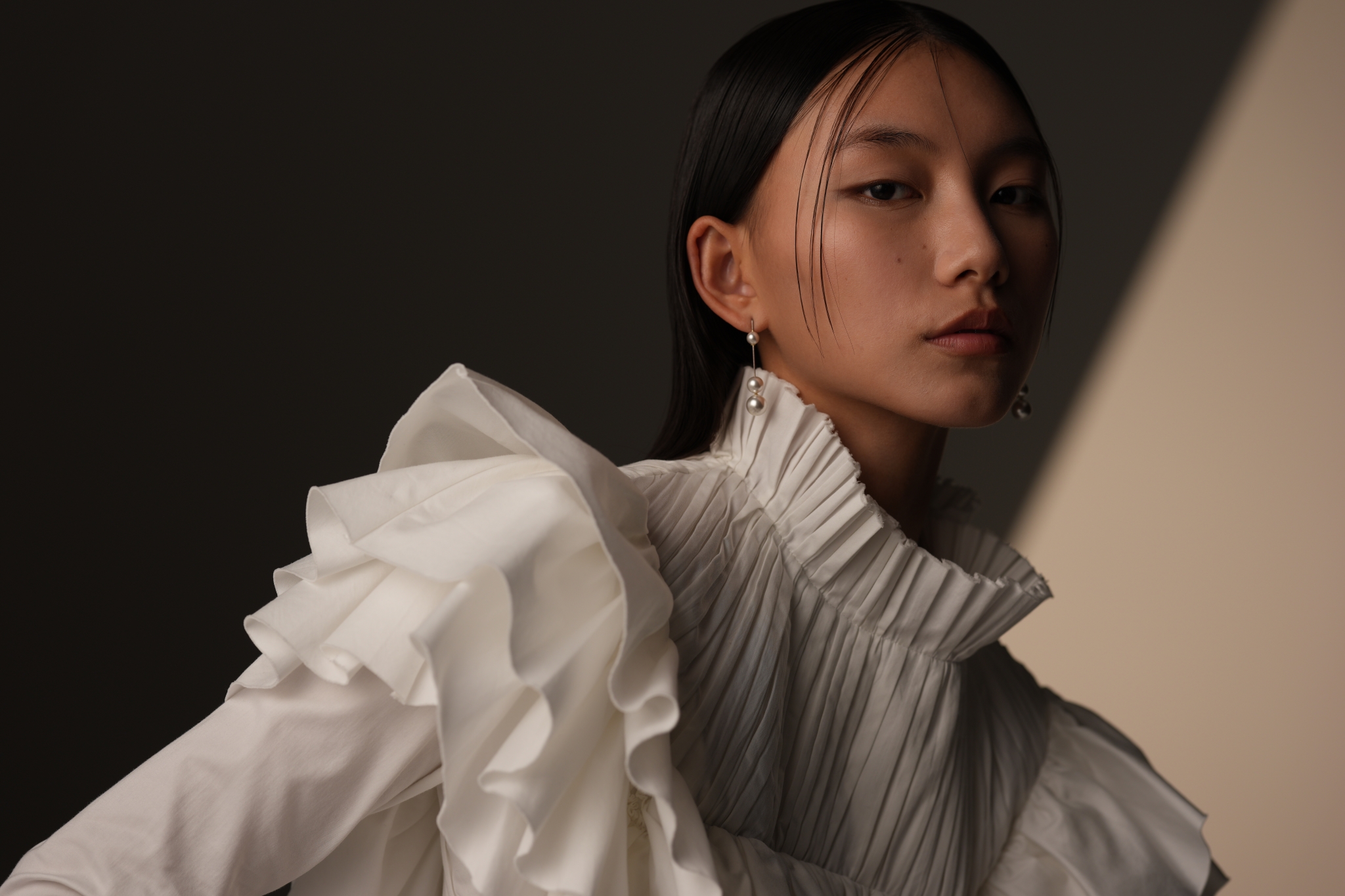 A bust-up portrait of a woman wearing a white frilled outfit Click to open modal