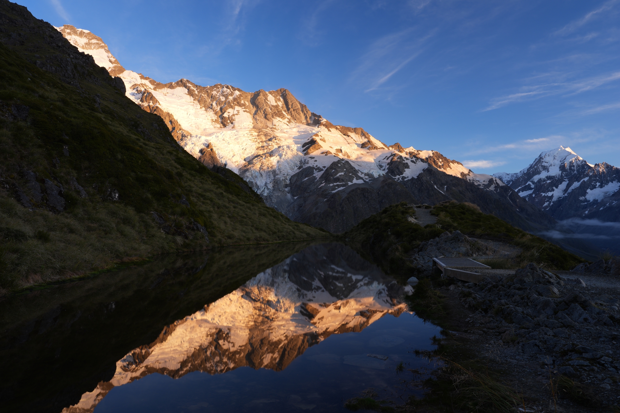 A landscape photo of snow-capped mountains reflected on a calm lake surface Click to open modal