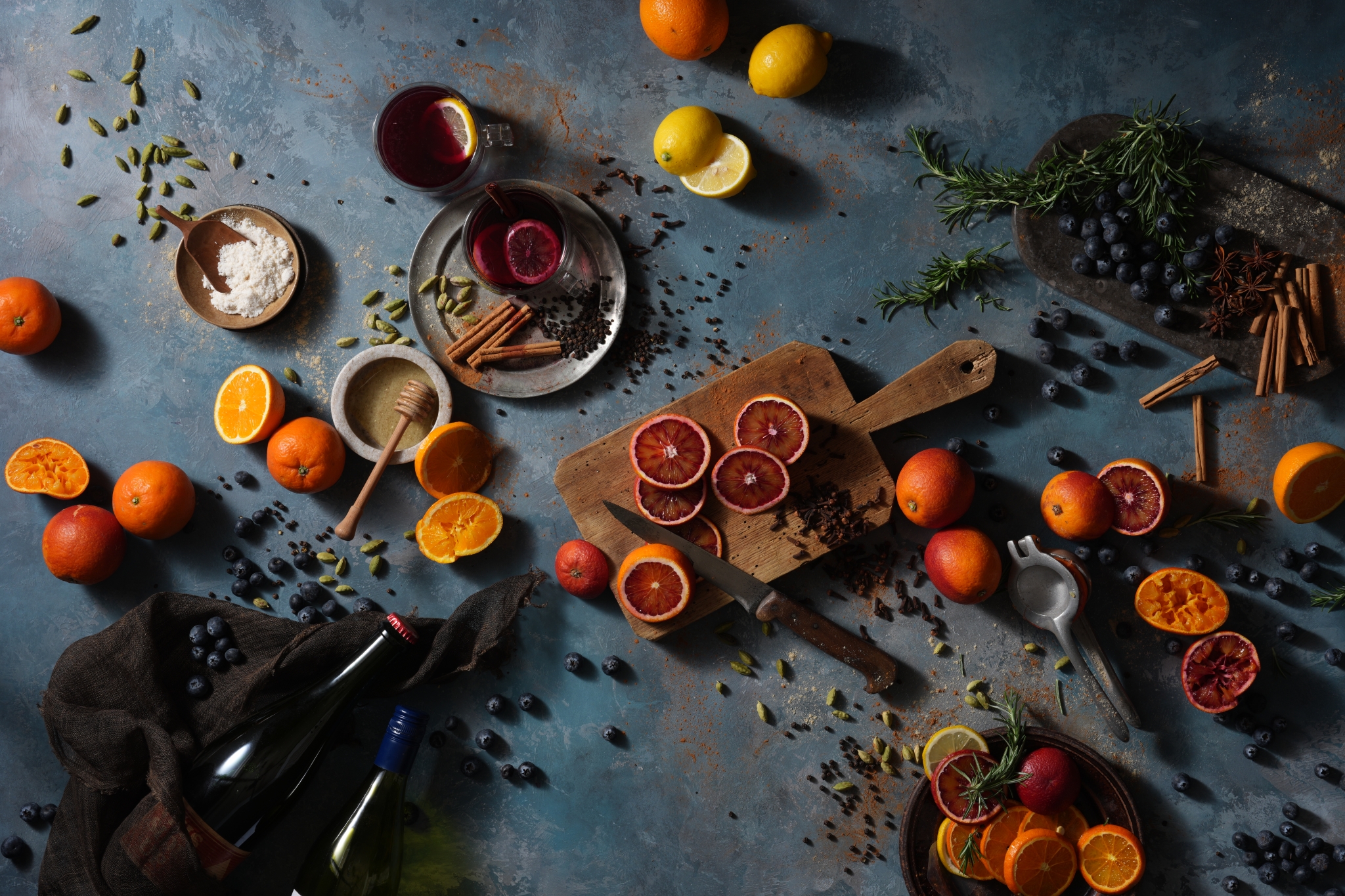 An overhead photo of food styling with citrus fruits, herbs, and cooking utensils arranged Click to open modal