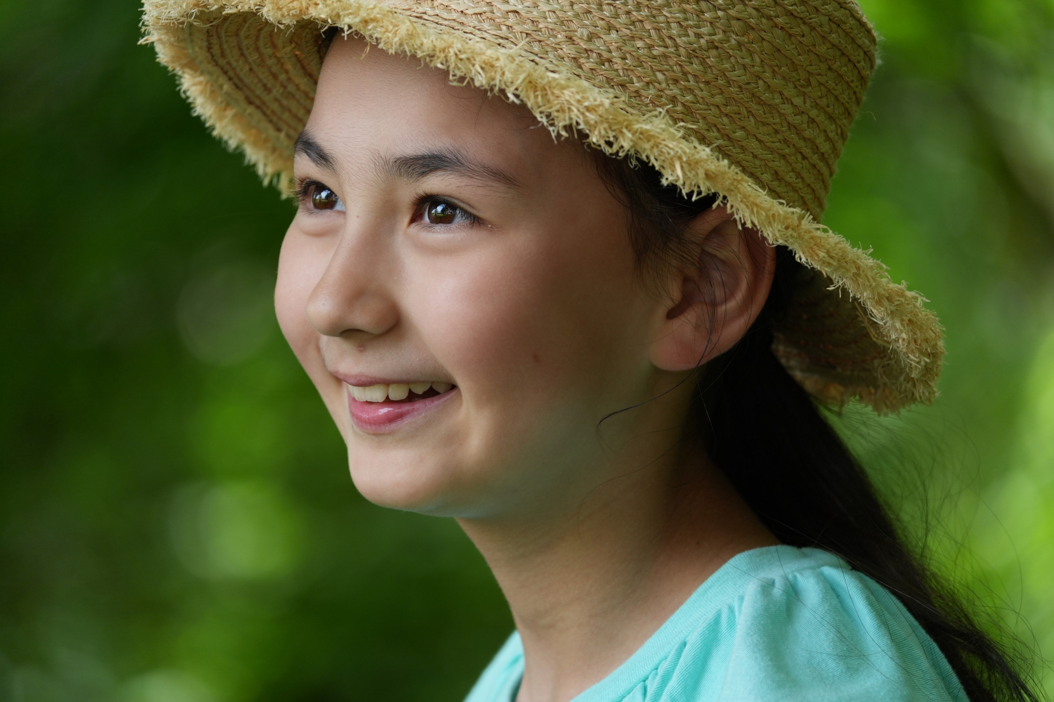 A woman wearing a hat gazes to her left with a gentle smile. Click to open modal