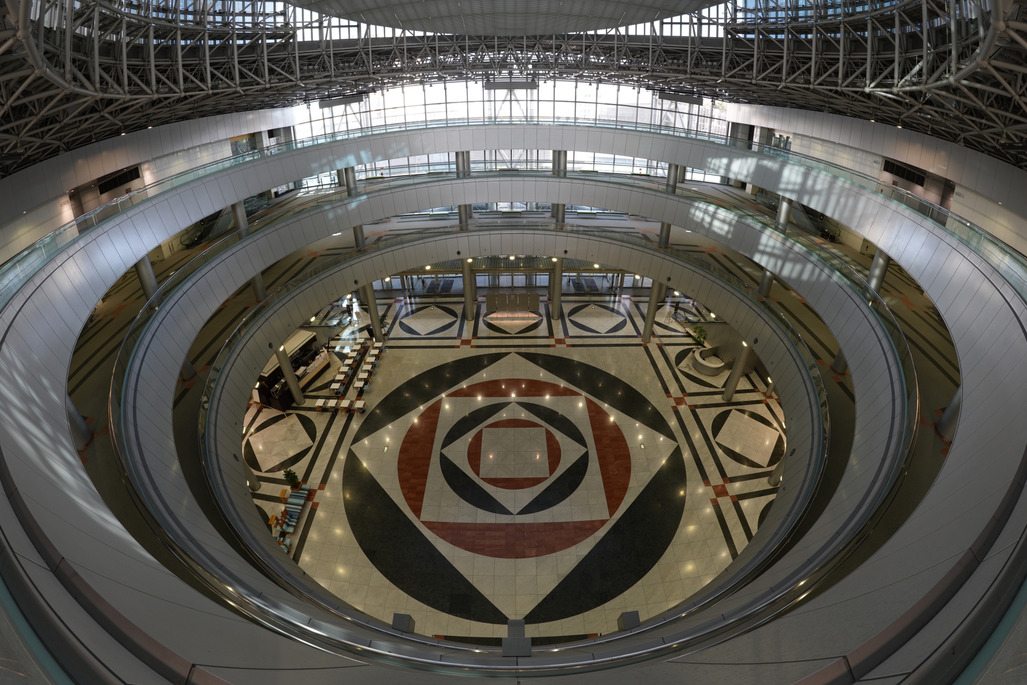 Overhead view of circular building with concentric architectural rings and ornate decorative pattern Click to open modal