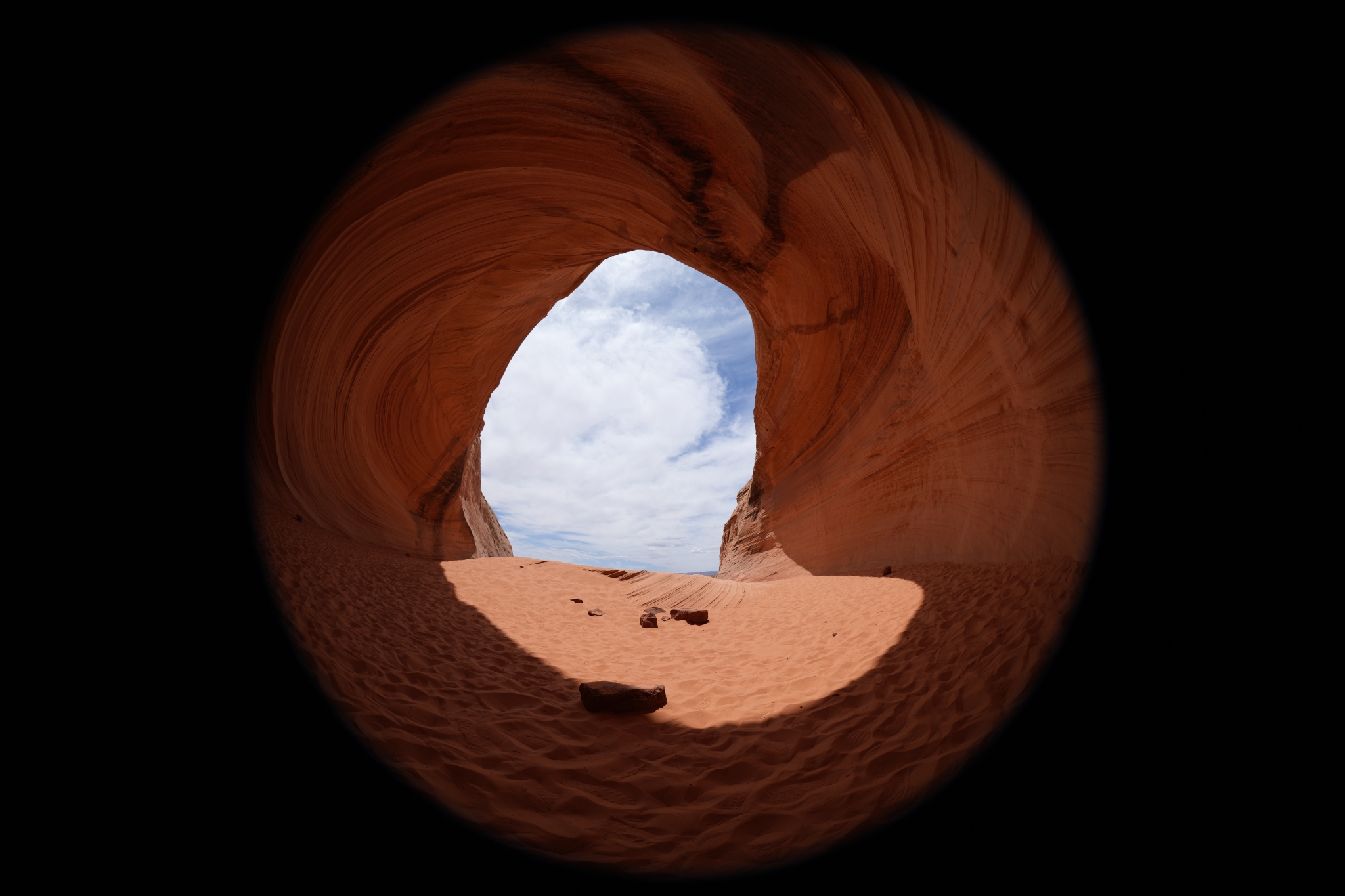 Cave entrance opening framing sky visible through aperture Click to open modal