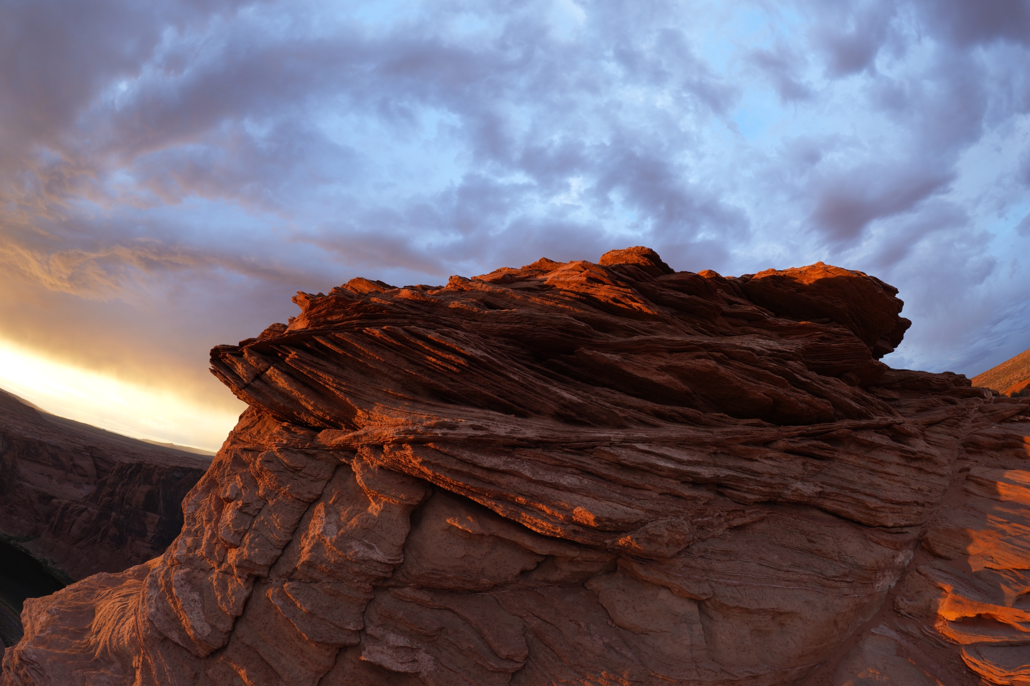 Rocky mountain ridge silhouetted against colorful sunset sky with orange and blue hues during dusk Click to open modal