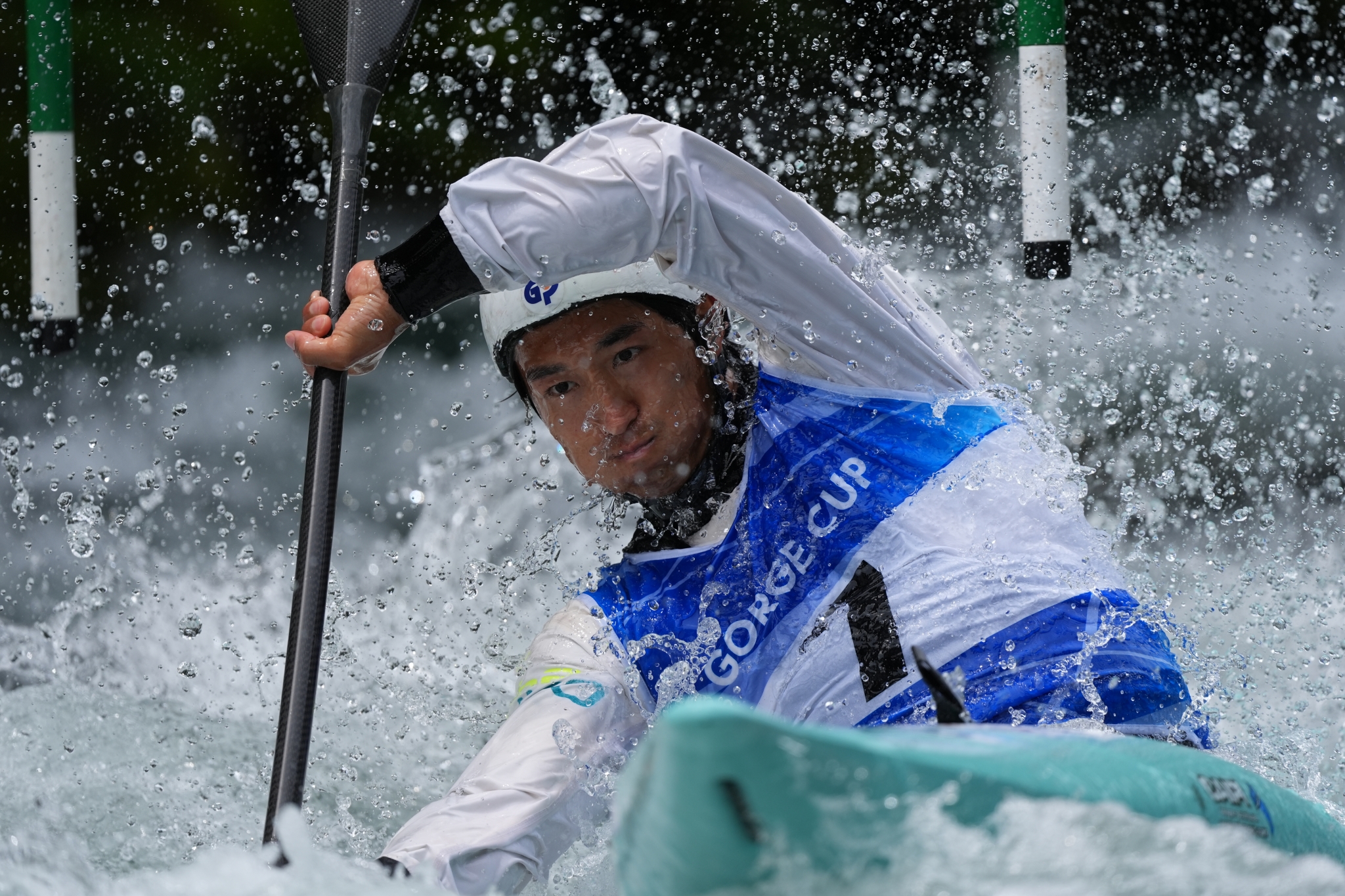 A canoe athlete paddles through splashing white water during a race. Click to open modal