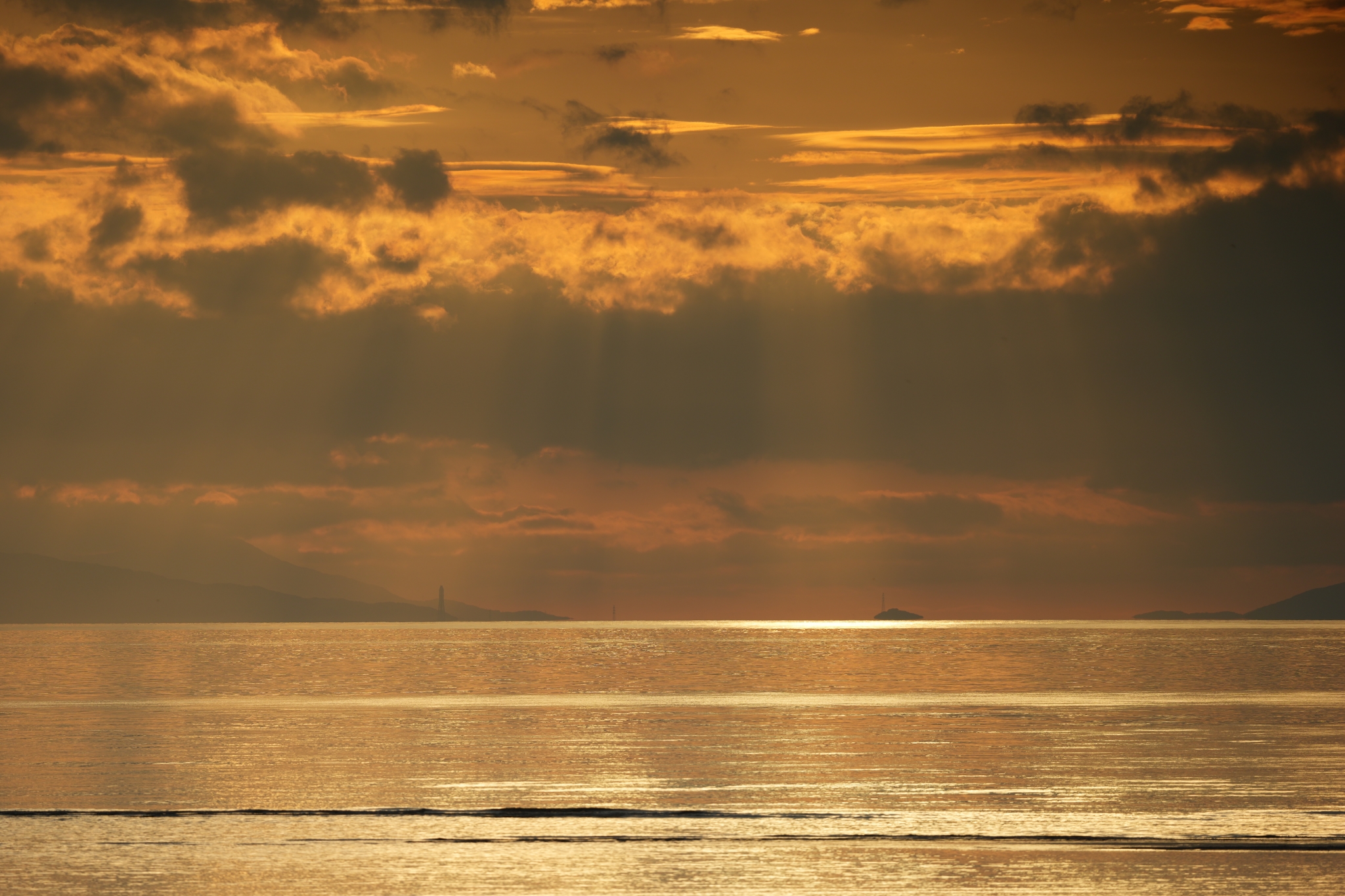 A golden sunset casts rays of light across a calm ocean surface. Click to open modal