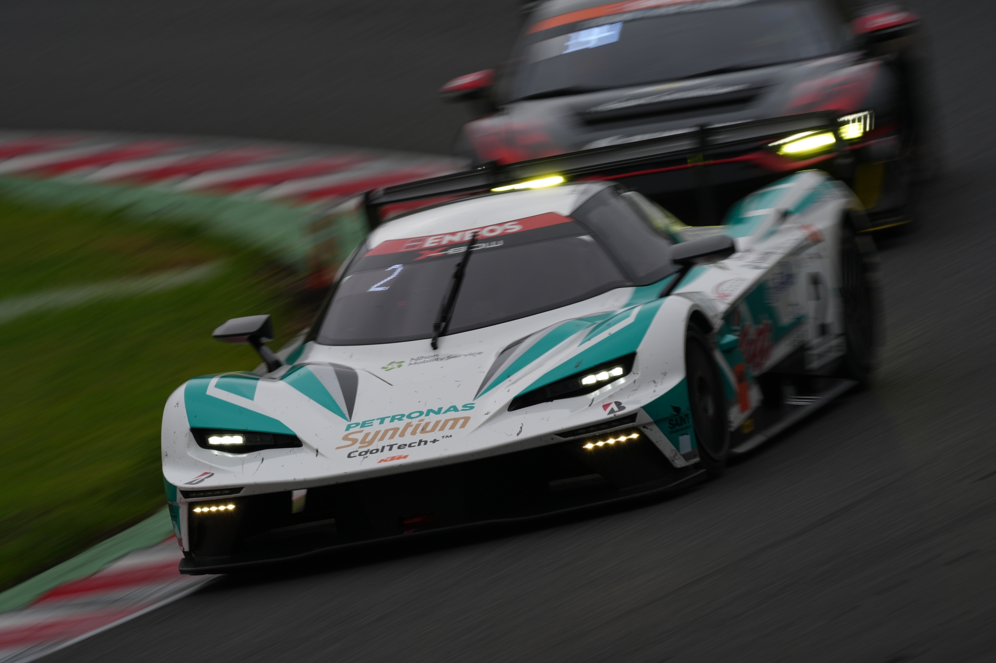 Racing cars speeding around a corner on a wet track Click to open modal