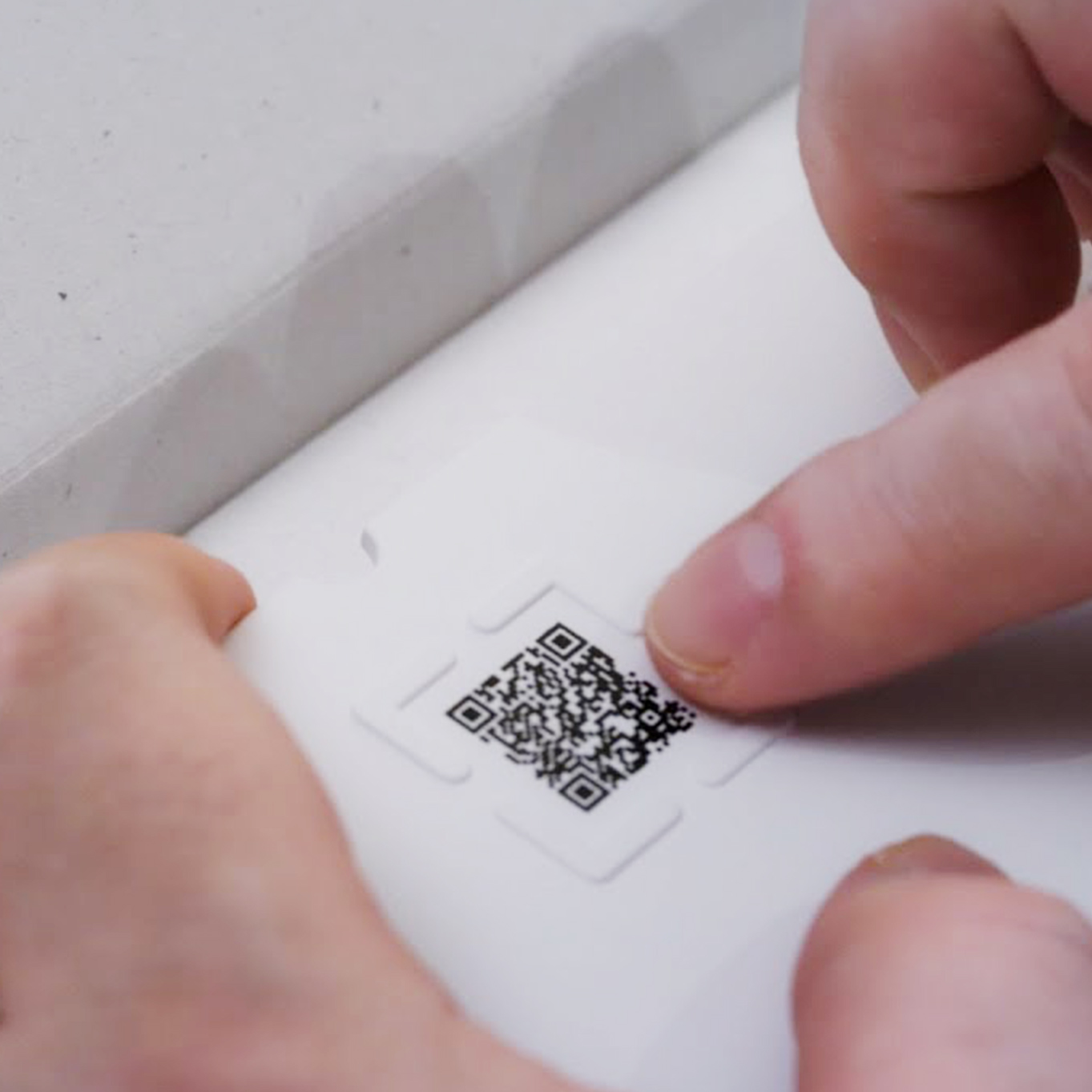 There is a protrusion around the QR code. The protrusions are touched with a finger.