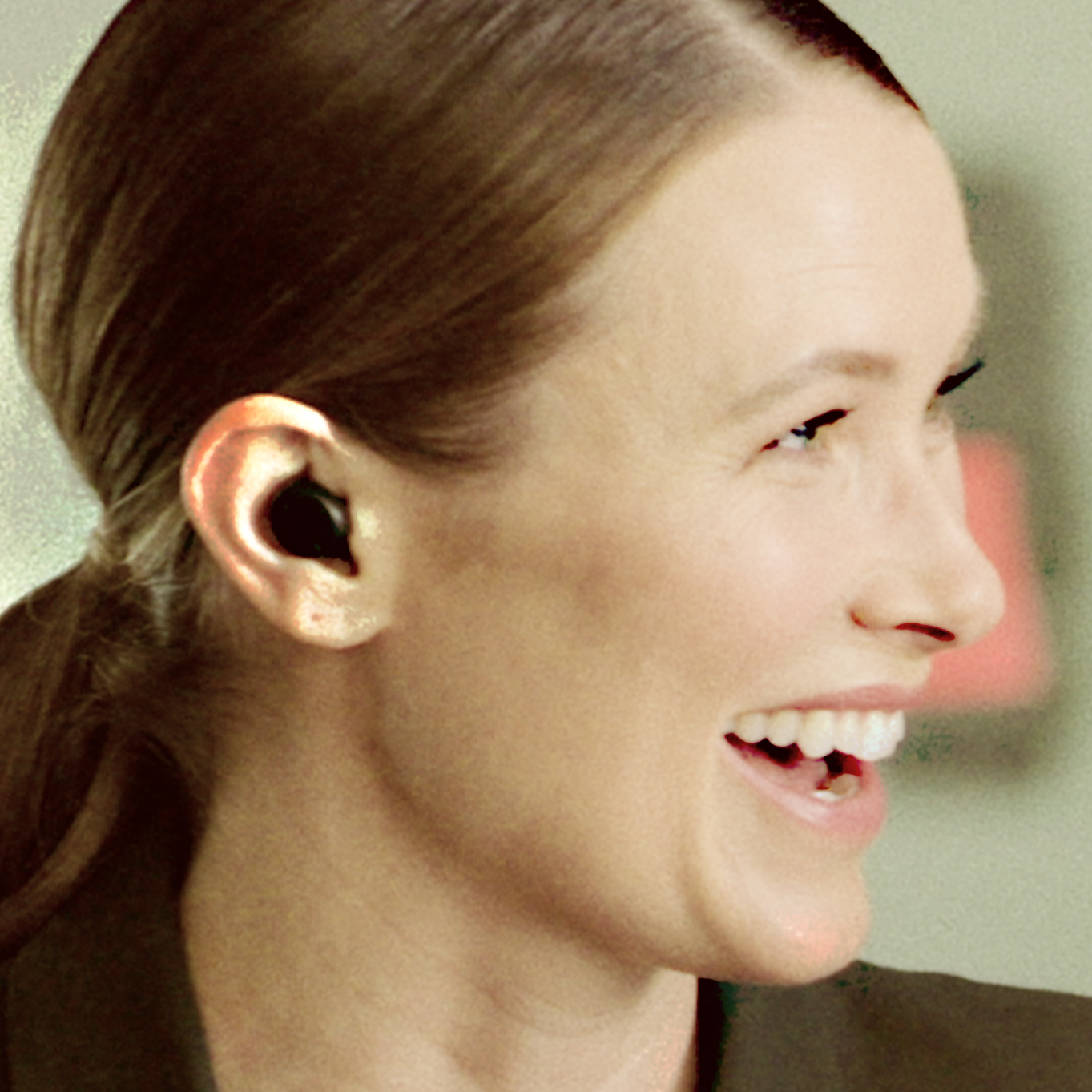 Profile of a woman. She wears hearing aids in her ears.